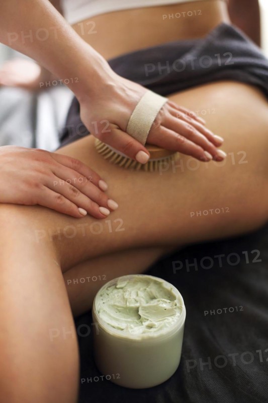 Unrecognizable female receiving anti cellulite massage with brush from professional masseuse in spa salon