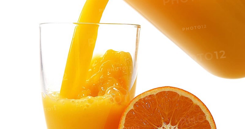 Orange Juice being poured into Glass against White Background