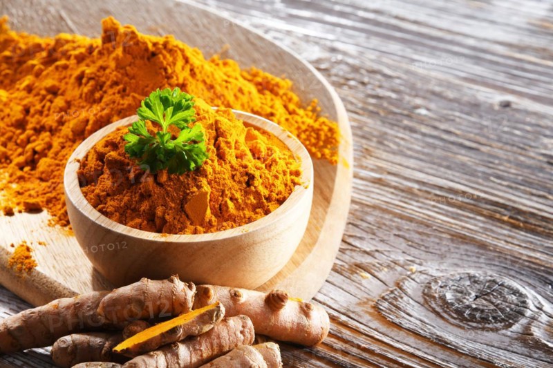 Composition with a bowl of ground turmeric and its fresh rhizome