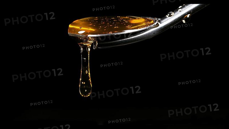 Honey Flowing from Spoon against Black Background