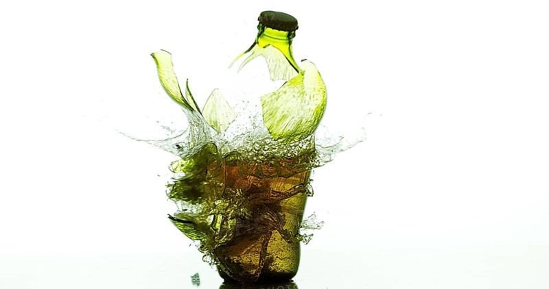 Bottle of Beer Breaking and Splashing against White Background