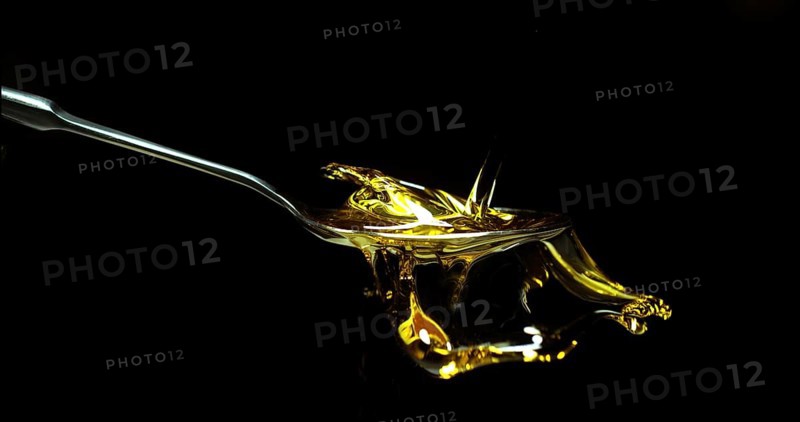 Olive Oil, Falling in a Spoon against Black Background