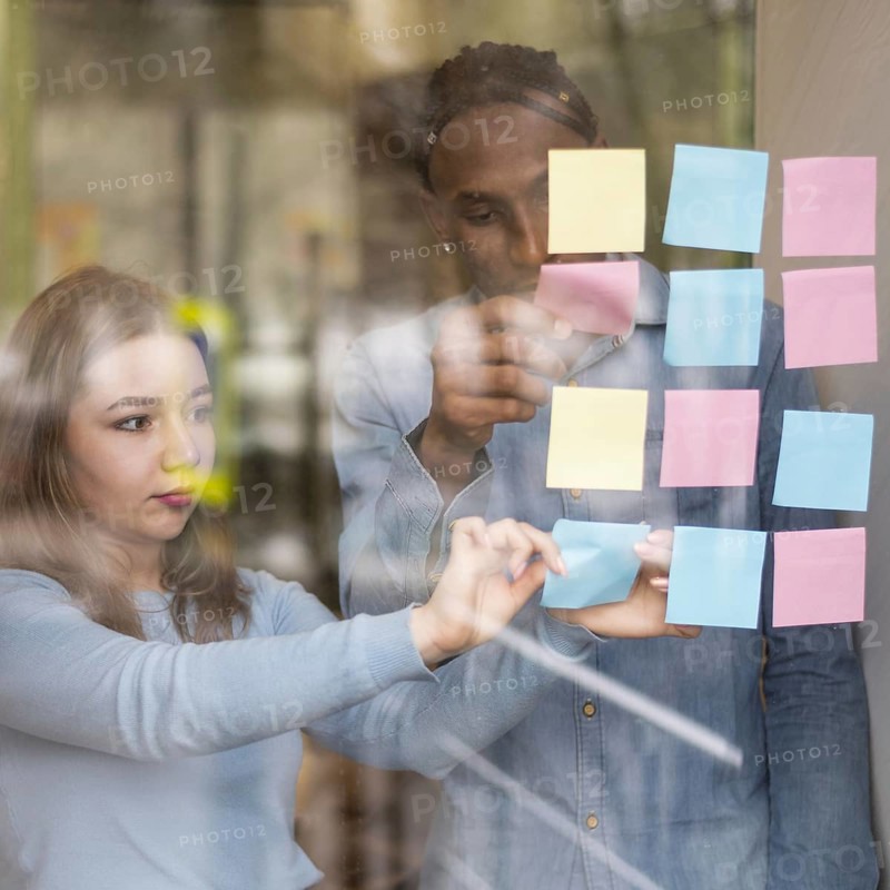 Front view man woman putting sticky notes office window