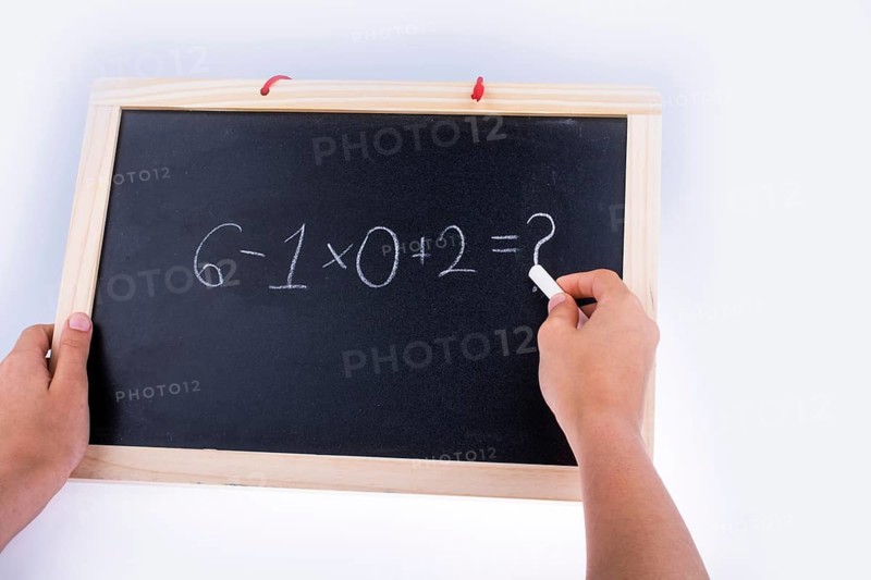 Hand writing a math problem on board with a chalk