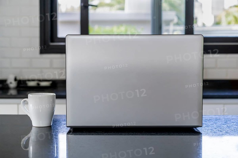 Laptop and cup of coffee on the kitchen island. Home office concept