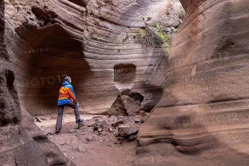 Tourist in sportswear visiting Slot Canyon Toba de Colores, Barranco de las Vacas, Agüimes, Las Palmas, Gran Canaria, Canary Islands