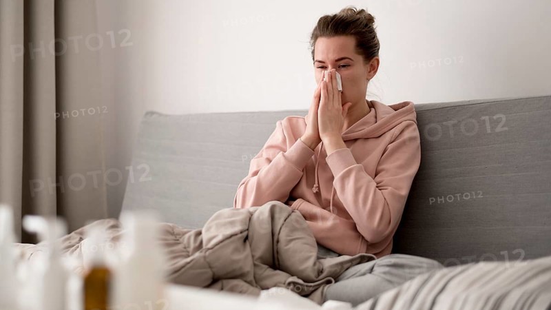 Woman indoors blowing her nose