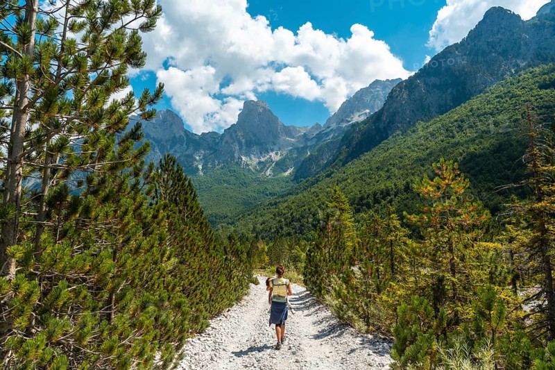 Woman hikers walking on Valbona Valley trail next to trees, Theth National Park, Albanian Alps, Albania, Europe