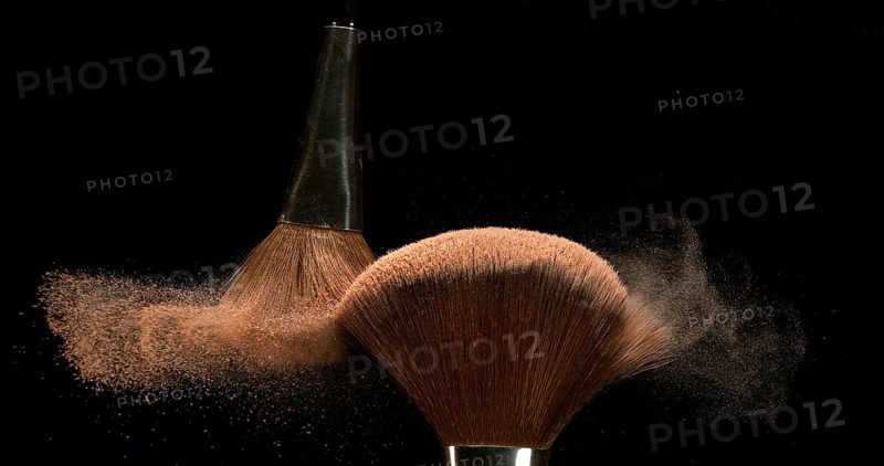 Make-up Brush spreading blush powder on black background