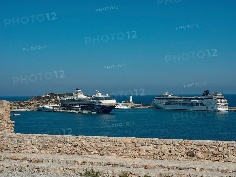 Cruise ships in the harbour with stone wall in the foreground under a clear blue sky, ibiza, mediterranean sea, spain