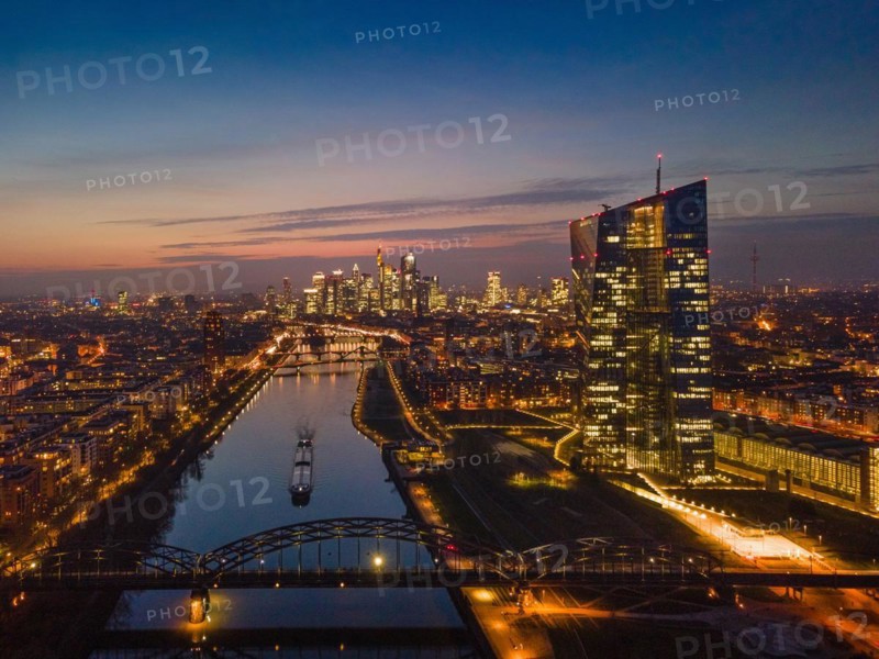 The lights of the European Central Bank (ECB) and the Frankfurt banking skyline glow in the evening. (Aerial view with a drone), Osthafen, Frankfurt am Main, Hesse, Germany, Europe