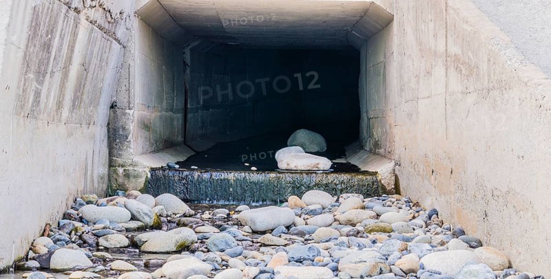 Concrete tunnel at Pebble Beach in South Korea with water running onto large rocks and stones, South Korea, Asia