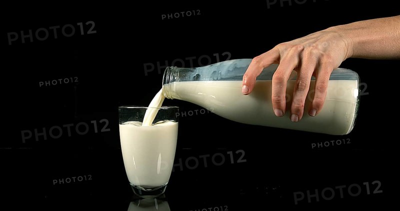 Milk being poured into Glass against black Background