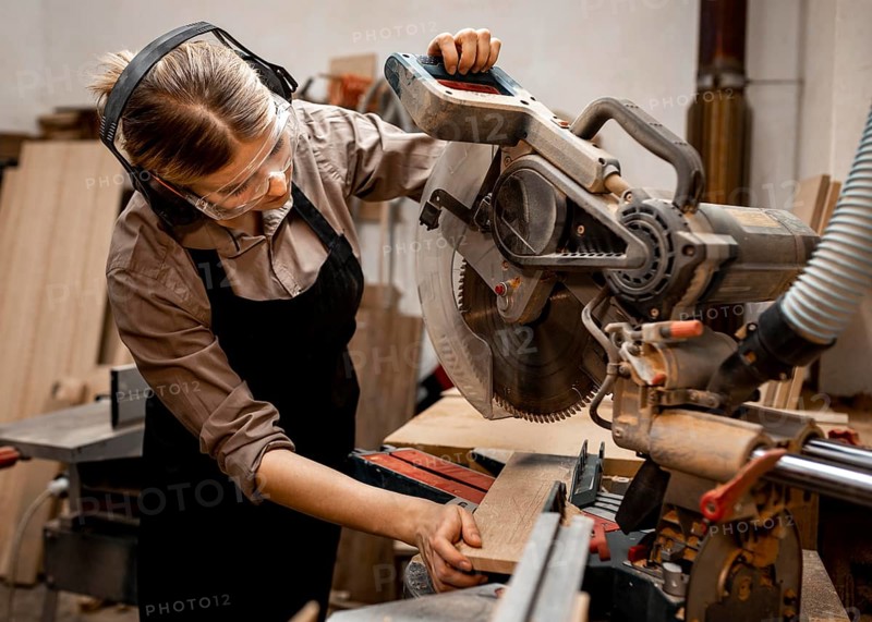 Female carpenter studio using electric saw