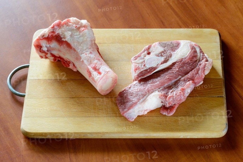 Meat of beef and marrowbone on a wooden cutting board, will be boil for the preparation of broth