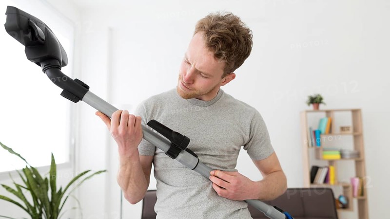 Man with vacuum cleaning house