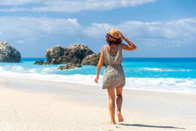 A woman walking on the turquoise water Megali Petra beach of Lefkada island, Ionian Sea, Greece, Europe