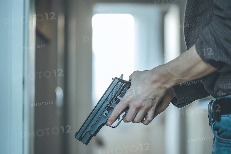 Undercover police agent is holding a black weapon in his hand, ready for shoot