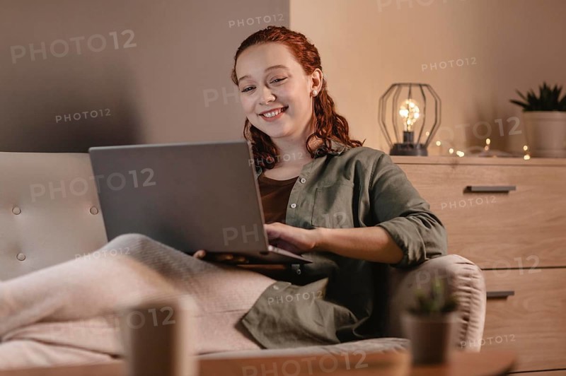 Smiley woman using laptop home couch