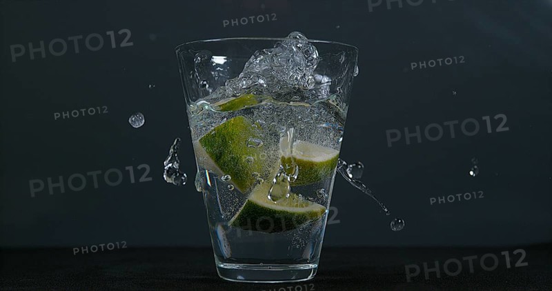 Green Citrus (citrus aurantifolia), falling into a Glass of Water
