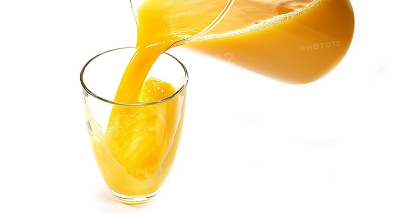 Orange Juice being poured into Glass against White Background