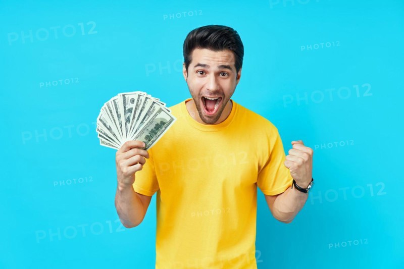 Happy excited man showing money banknotes on blue background. Business, win, income, success concept