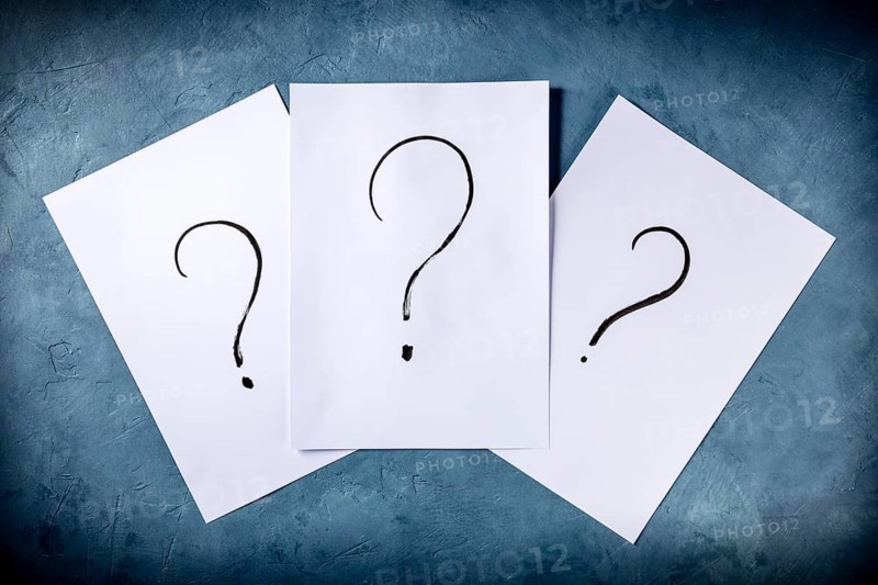 Question marks, written in ink on a piece of standard office paper, shot from the top