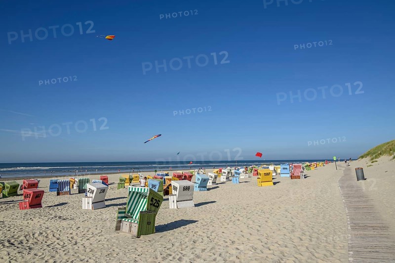 Colourful beach chairs and kites on a sunny beach with blue sky and sea, langeoog, east frisia, germany