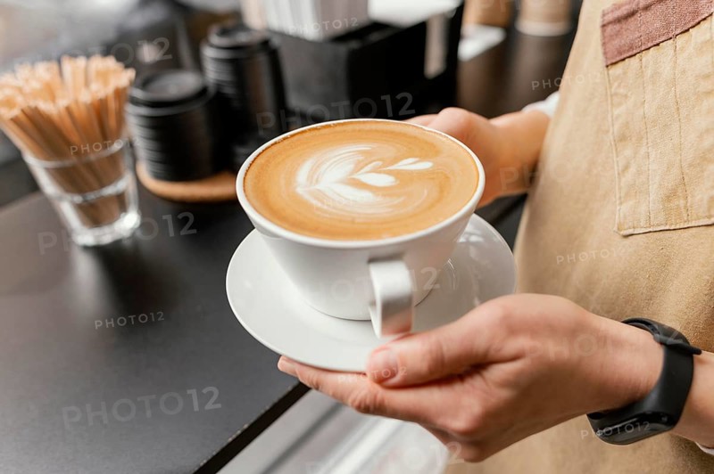 Side view female barista holding decorated cup coffee hands