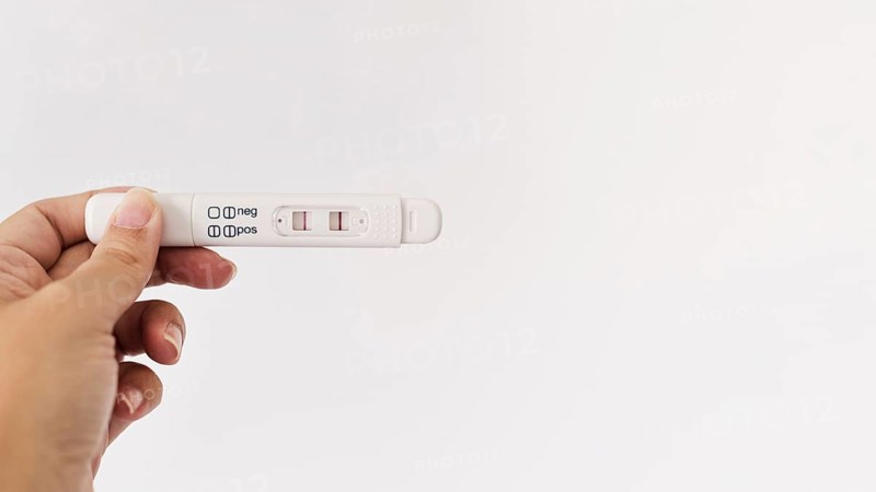 Hand holding positive pregnancy test