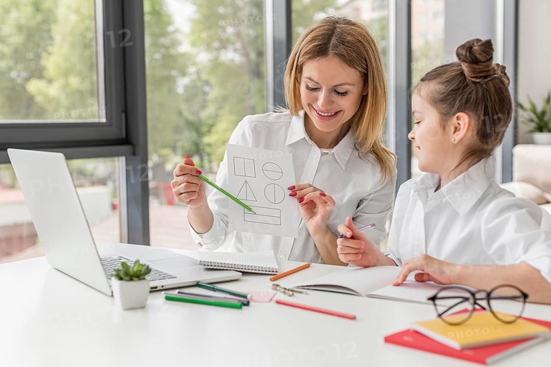 Teacher helping her daughter study indoors
