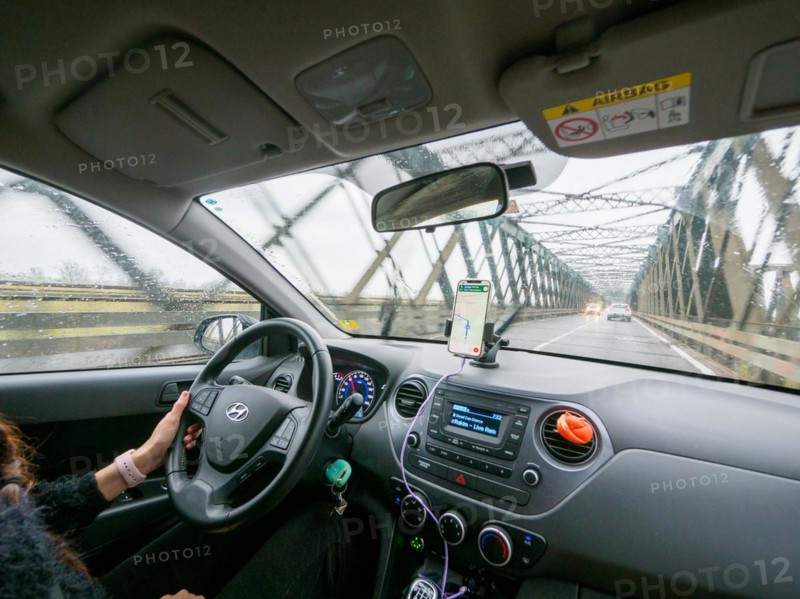 View from inside a car on a rainy day driving over a bridge with a phone for navigation, A1 A8 highway near Milan, Italy, Europe