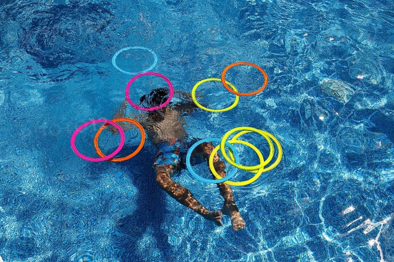 Boy playing with colourful rings in swimming pool, Province of Quebec, Canada, North America