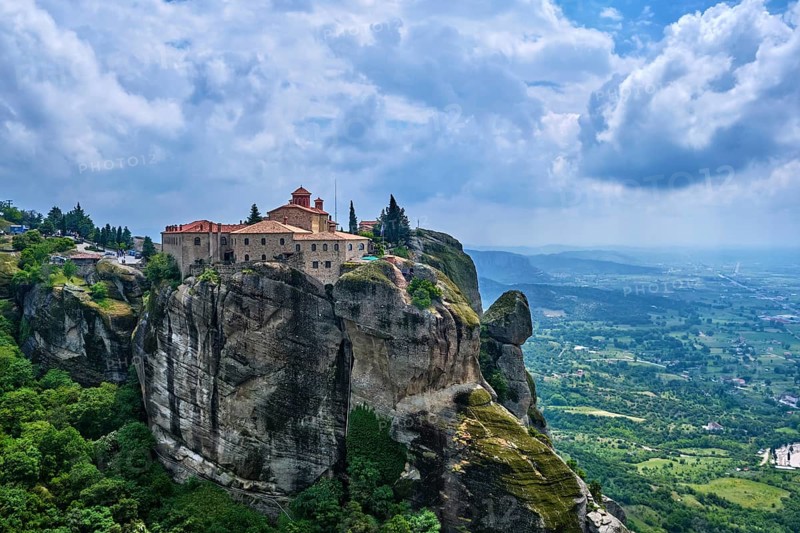 Clifftop Eastern Orthodox nunnery of St Stephen or Agios Stefanos in famous Meteora valley, Greece, listed as UNESCO World Heritage, overlooking villages of Kastraki and Kalampaka at foot of mountains on spring day, Europe