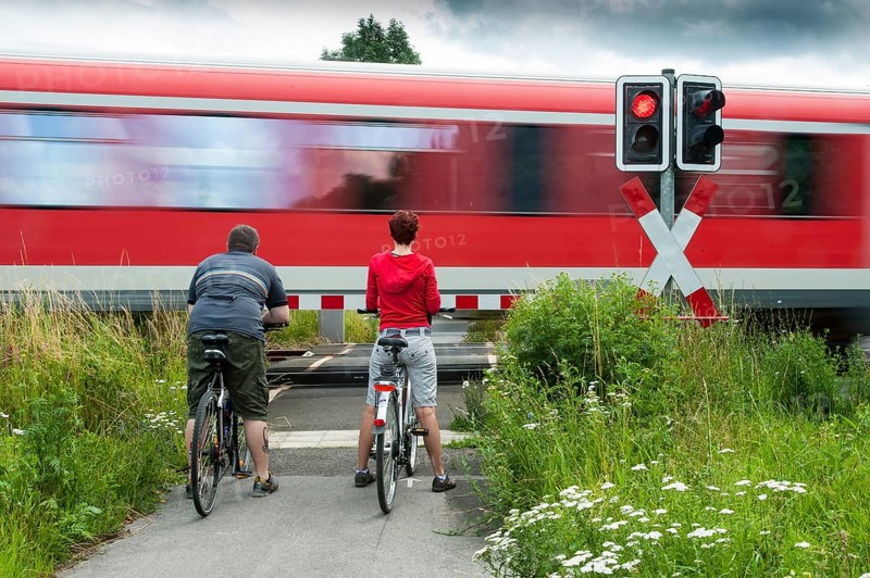 Man and woman standing with bicycles at a closed railway crossing