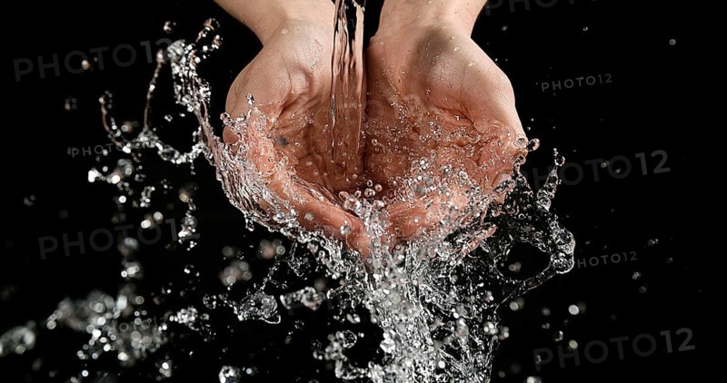 Hands of Woman and Water against Black Background