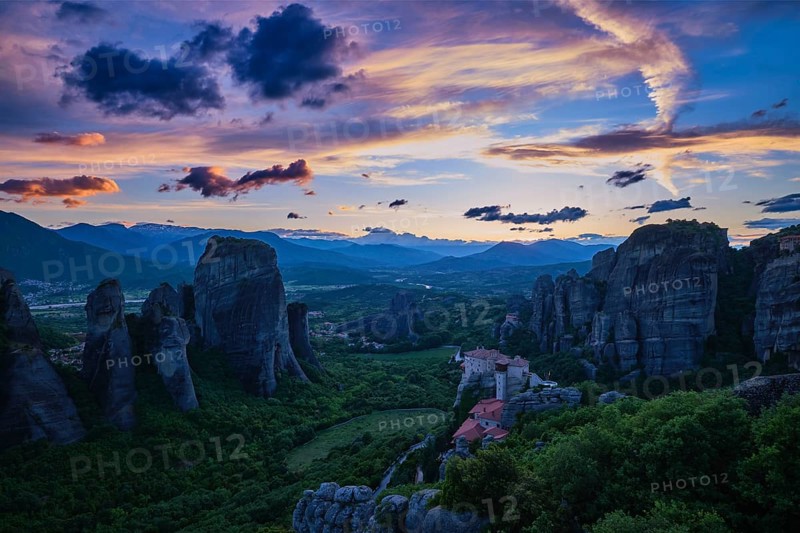 Twilight view of Meteora valley. Valley in blue shadows, clifftop Moni Agias Varvaras Roussanou nunnery and rocks and cliffs. Beautiful sky in sunset colors, colorful clouds. Greece, UNESCO World Heritage