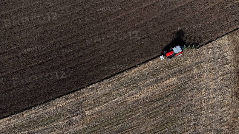 A red tractor ploughs a harvested field, dark soil, bird's eye view, drone shot, Upper Bavaria, Bavaria, Germany, Europe