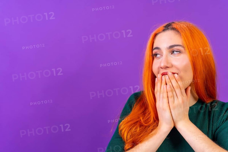 Redhead woman in studio photography making the gesture please on a purple background