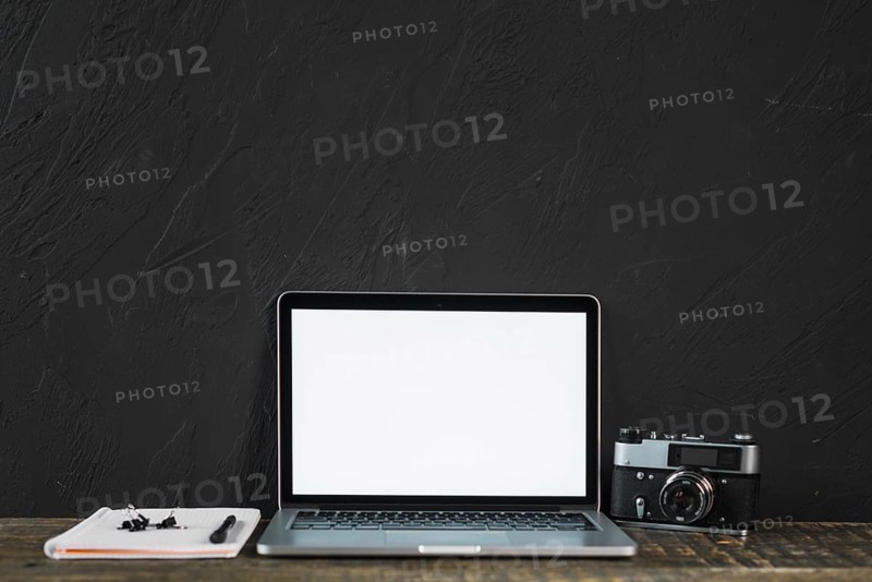 Retro old camera blank screen laptop with stationeries wooden table