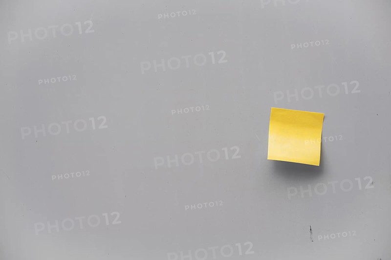 Yellow post-it note on a grey wall