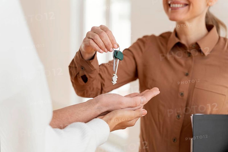 Smiley female realtor handing couple keys their new home