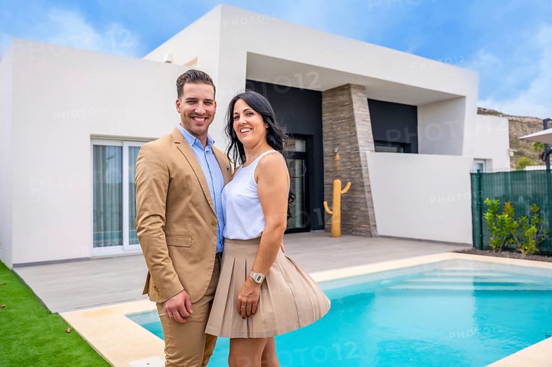 Portrait of a happy couple standing on the pool of their new luxury home
