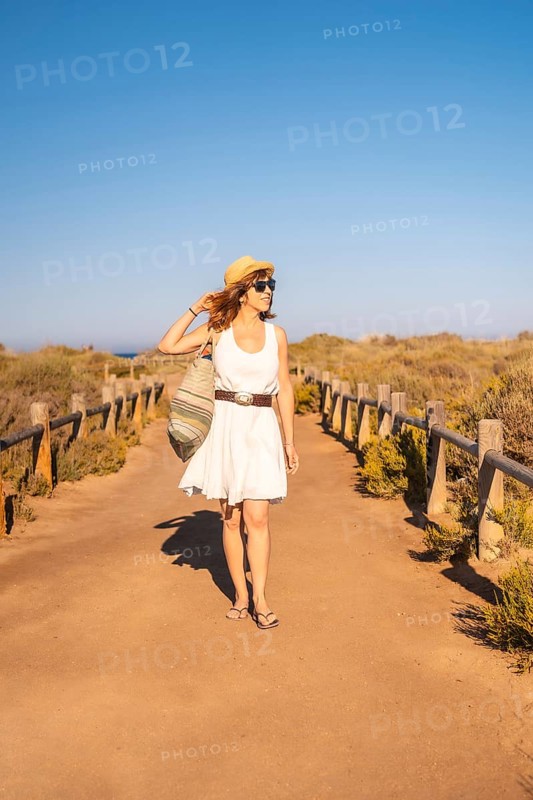 Vertical photo of a woman walking with a beach bag along a marked trail in Cabo de Gata, Spain, Europe