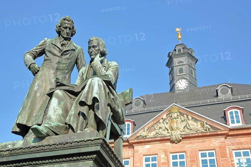 Brothers Grimm national monument, standing Jacob and sitting on the chair Wilhelm and baroque Neustadt town hall, brothers, bronze sculpture, poet, two, book, reading, German Fairy Tale Route, market square, Hanau, Hesse, Germany, Europe