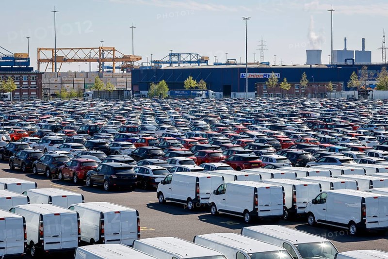 Duisburg, North Rhine-Westphalia, Germany - New cars and vans, car terminal in Duisburg harbour, cranes in the container harbour behind