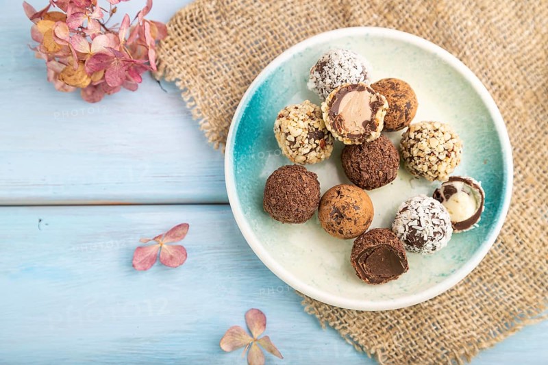 Chocolate truffle candies with cup of coffee on a blue wooden background and linen textile. top view, flat lay, close up