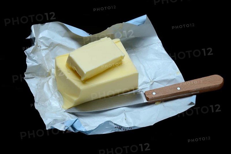 A piece of butter with packaging and kitchen knife