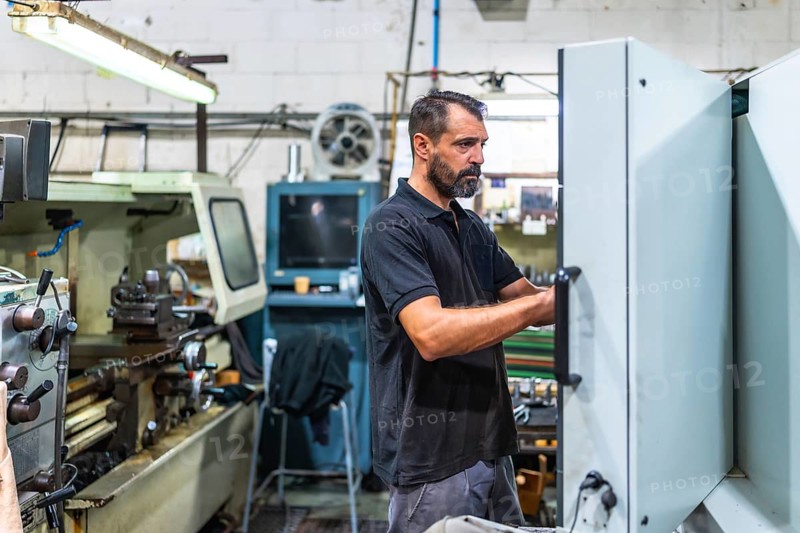 Mature caucasian male operator working in the control panel of cnc factory