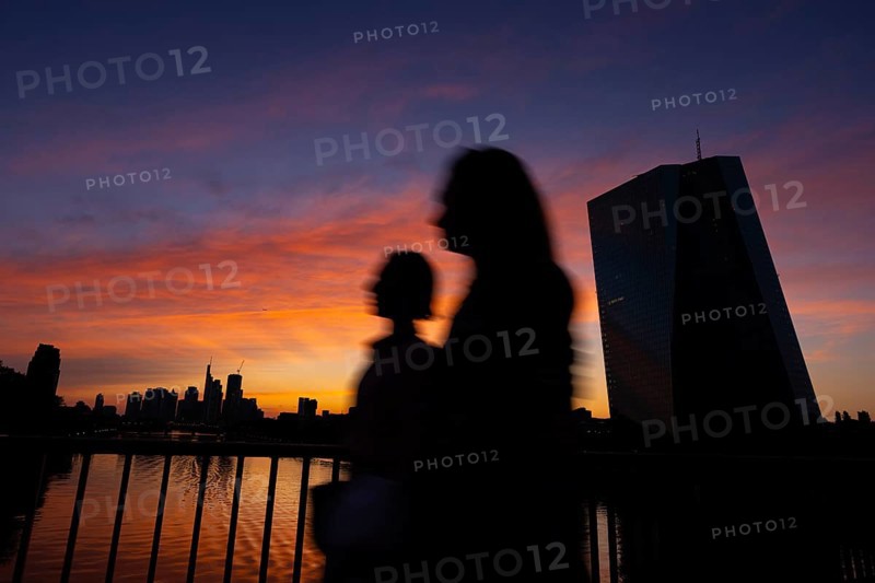 The light of the setting sun colours the sky behind the European Central Bank (ECB) and the Frankfurt skyline orange-red, Frankfurt am Main, Hesse, Germany, Europe